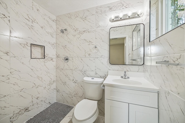 bathroom with tile walls, toilet, vanity, and a tile shower