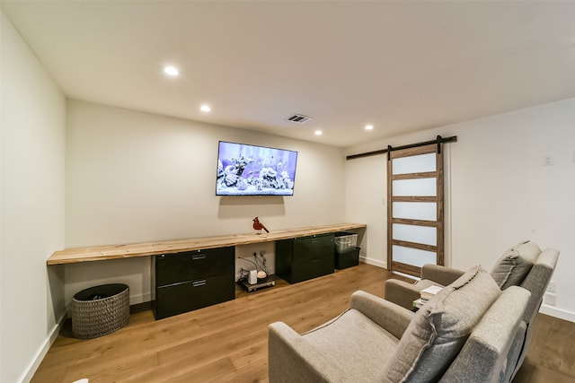 living room with a barn door, hardwood / wood-style floors, and built in desk