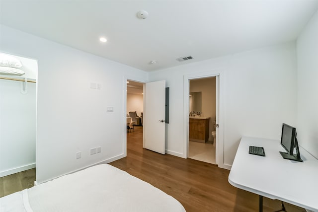 bedroom with a closet, connected bathroom, and dark hardwood / wood-style flooring