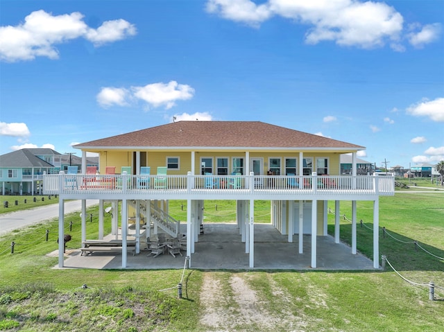 back of house featuring a lawn, a wooden deck, and a patio