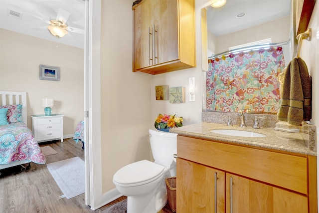 bathroom with hardwood / wood-style floors, vanity, ceiling fan, and toilet