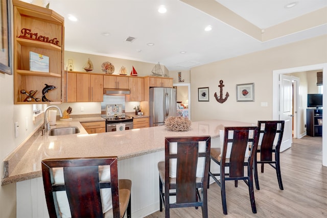 kitchen featuring kitchen peninsula, light wood-type flooring, stainless steel appliances, sink, and a breakfast bar area