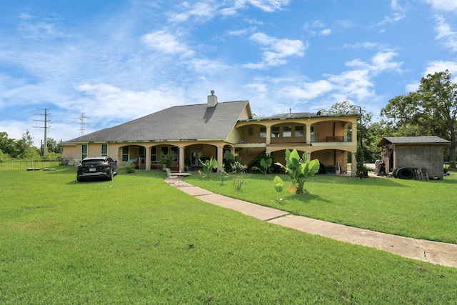 view of front of house featuring a front lawn and a storage unit