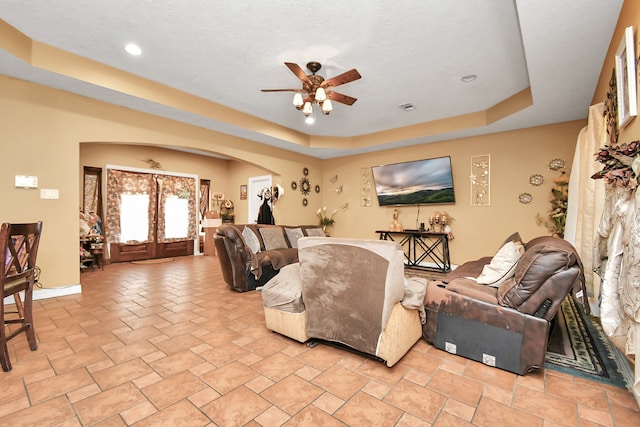 living room featuring a tray ceiling, french doors, and ceiling fan