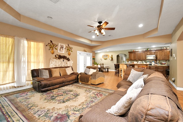 living room with ceiling fan, a wealth of natural light, and a textured ceiling