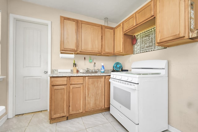 kitchen featuring white range, light stone counters, light tile patterned floors, and sink