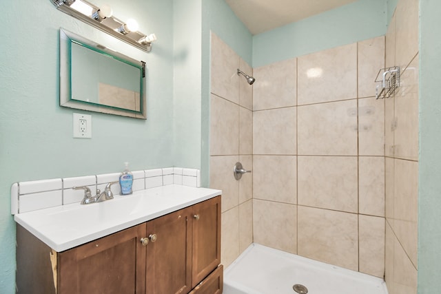 bathroom with tiled shower and vanity