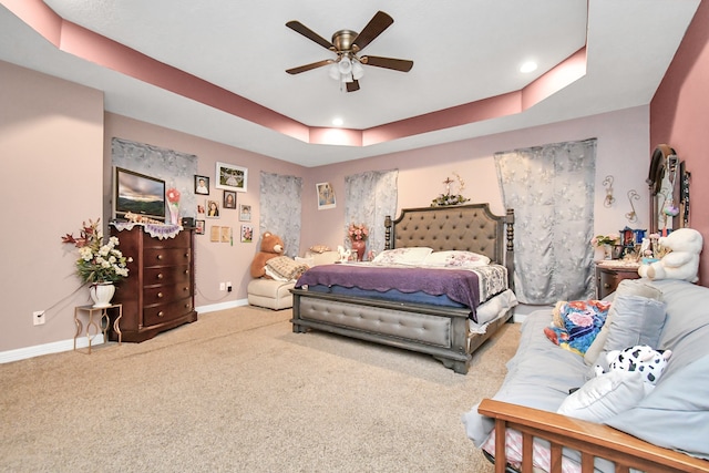 bedroom with a raised ceiling, ceiling fan, and carpet flooring