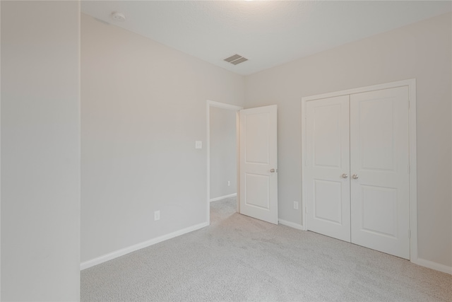 unfurnished bedroom with a closet and light carpet