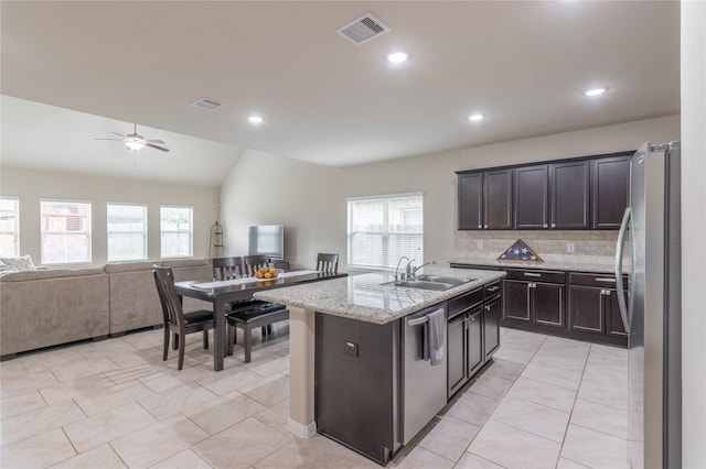 kitchen featuring vaulted ceiling, appliances with stainless steel finishes, an island with sink, sink, and ceiling fan