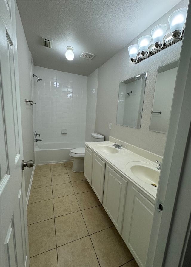 full bathroom with tile patterned flooring, tiled shower / bath, toilet, vanity, and a textured ceiling