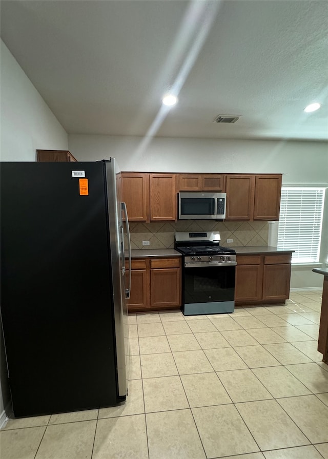 kitchen featuring stainless steel appliances, light tile patterned floors, and tasteful backsplash