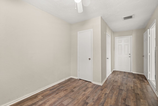 unfurnished bedroom featuring dark hardwood / wood-style flooring, ceiling fan, and a textured ceiling