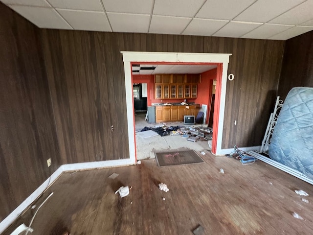 empty room with a paneled ceiling, hardwood / wood-style flooring, and wooden walls