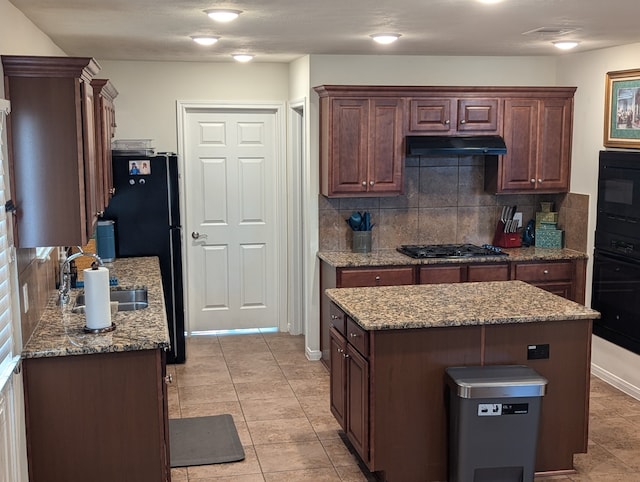 kitchen featuring tasteful backsplash, a center island, black appliances, and sink