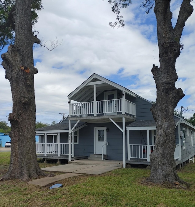 view of front facade featuring entry steps, a front lawn, and a balcony