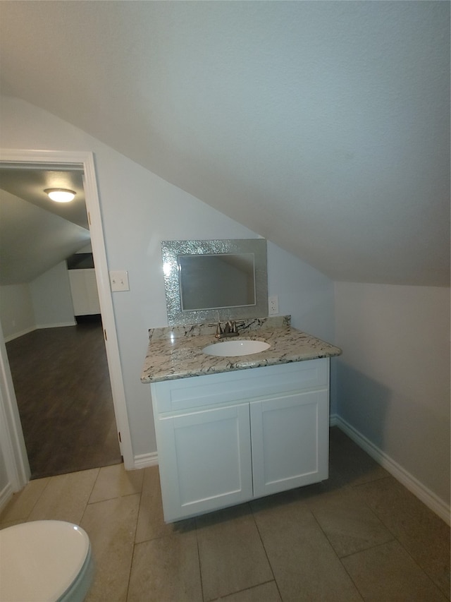 bathroom featuring lofted ceiling, vanity, toilet, and tile patterned floors