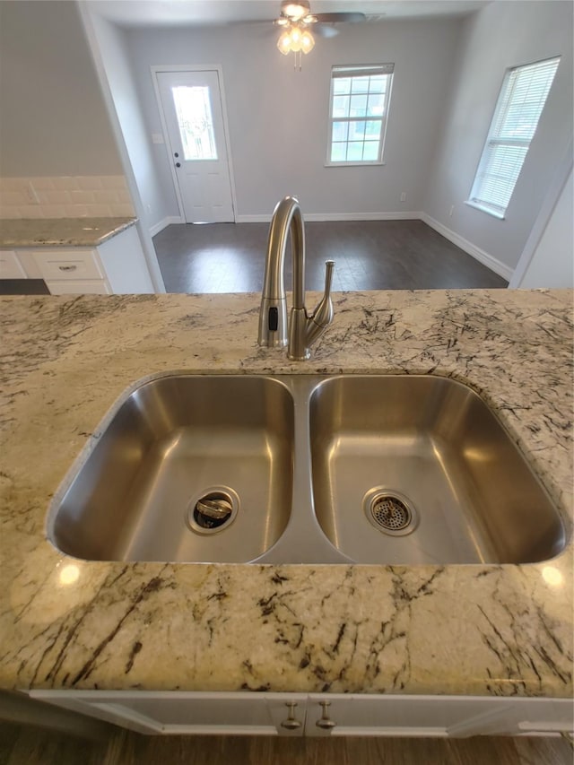 details with dark wood-style flooring, light stone counters, white cabinets, ceiling fan, and a sink