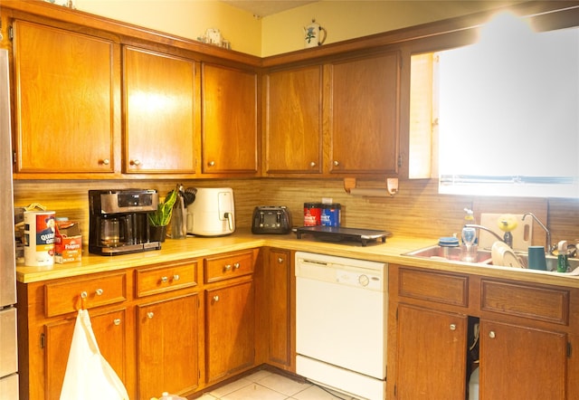 kitchen with dishwasher, light tile patterned floors, backsplash, and sink