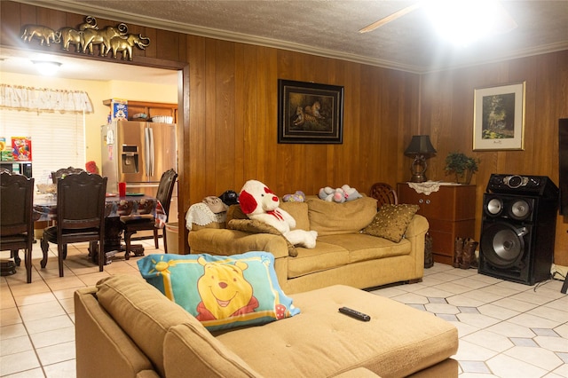 living room with a textured ceiling, wood walls, light tile patterned floors, and crown molding