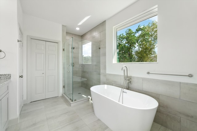 bathroom with vanity, tile walls, plus walk in shower, and tile patterned flooring