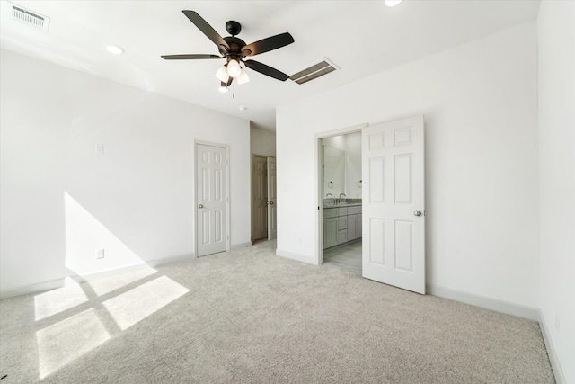 unfurnished bedroom with ceiling fan, light colored carpet, ensuite bathroom, and sink