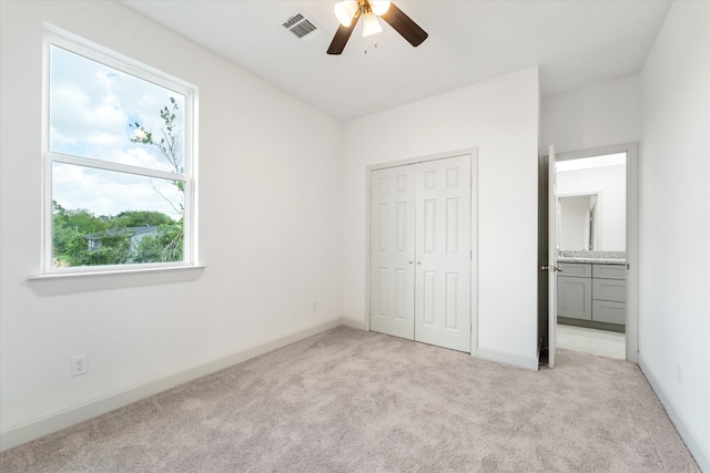 unfurnished bedroom featuring light colored carpet, ceiling fan, and a closet