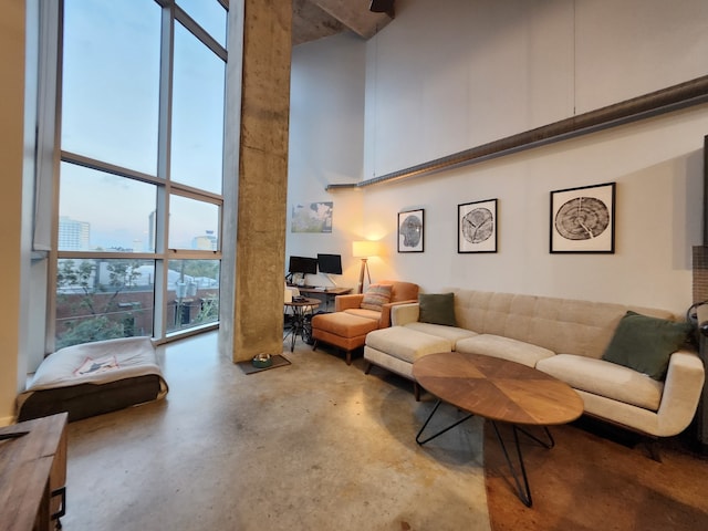 living room featuring a towering ceiling, expansive windows, and concrete floors