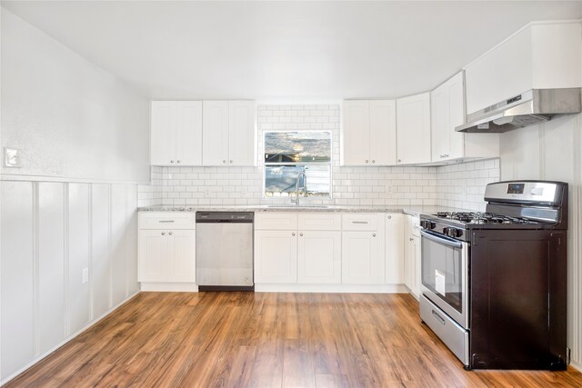 kitchen with appliances with stainless steel finishes, white cabinets, and light hardwood / wood-style floors