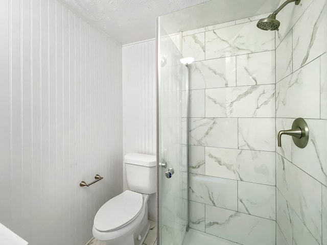 bathroom with toilet, a tile shower, and a textured ceiling