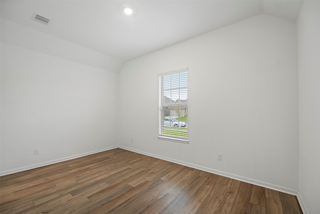 spare room with vaulted ceiling and hardwood / wood-style floors