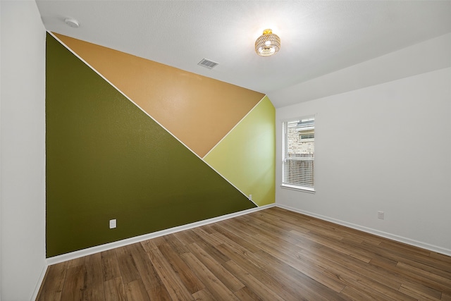 unfurnished room featuring vaulted ceiling and wood-type flooring