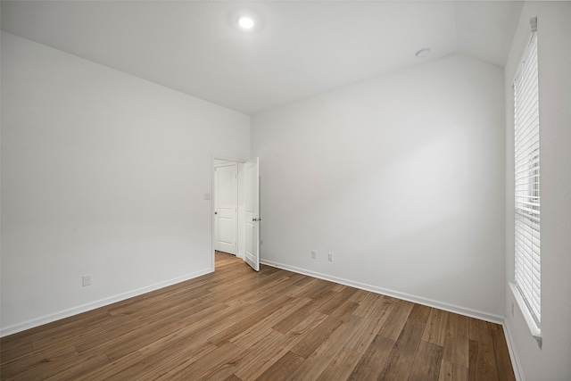 unfurnished room featuring vaulted ceiling, plenty of natural light, and wood-type flooring