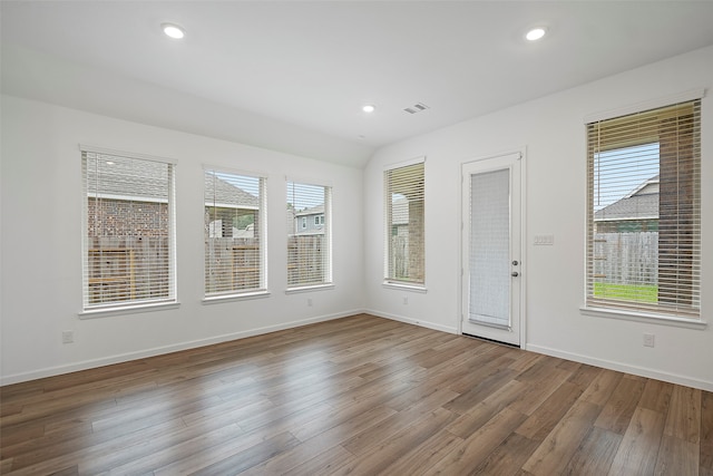 unfurnished room with lofted ceiling, hardwood / wood-style flooring, and a wealth of natural light