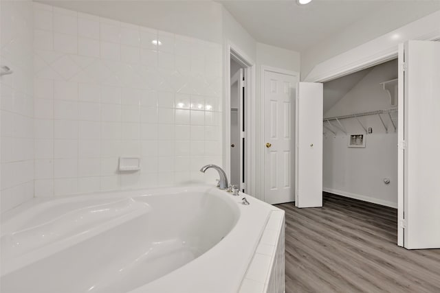 bathroom featuring wood-type flooring and tiled bath