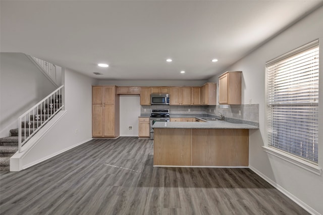 kitchen with dark hardwood / wood-style flooring, backsplash, appliances with stainless steel finishes, kitchen peninsula, and sink