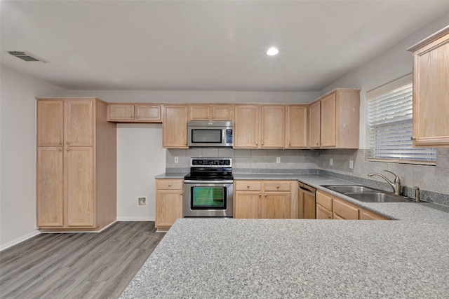 kitchen with stainless steel appliances, sink, tasteful backsplash, and light hardwood / wood-style floors