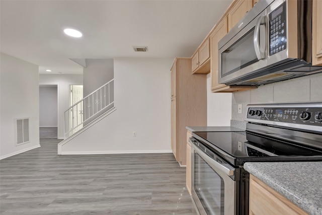 kitchen with light brown cabinets, appliances with stainless steel finishes, and light hardwood / wood-style floors