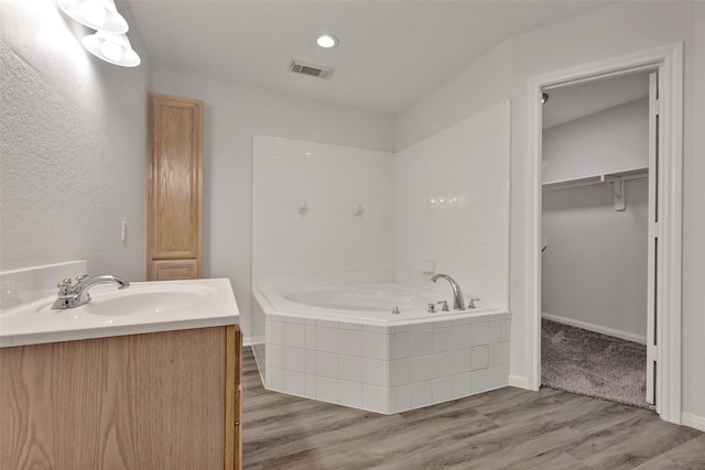 bathroom featuring vanity, hardwood / wood-style flooring, and tiled bath