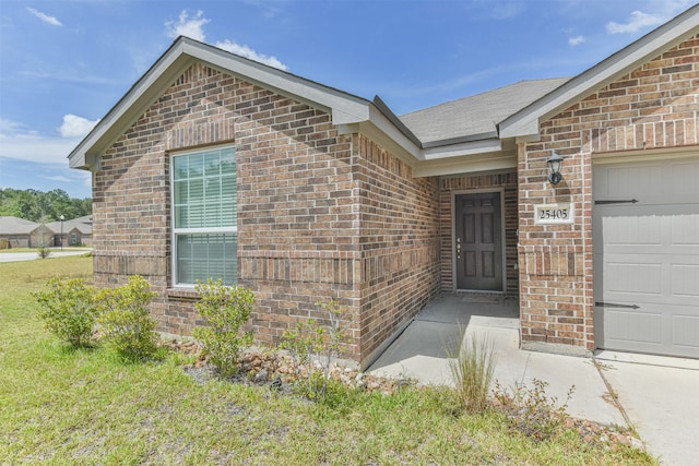 property entrance with a lawn and a garage