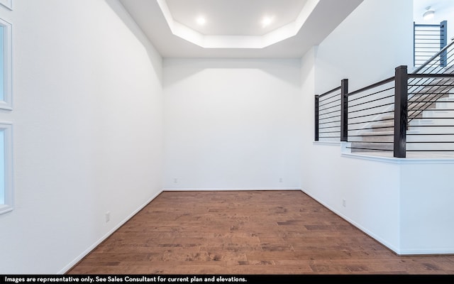 unfurnished room featuring wood-type flooring and a tray ceiling