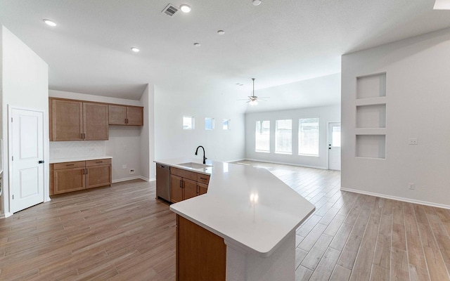 kitchen with sink, light hardwood / wood-style flooring, dishwasher, an island with sink, and built in features