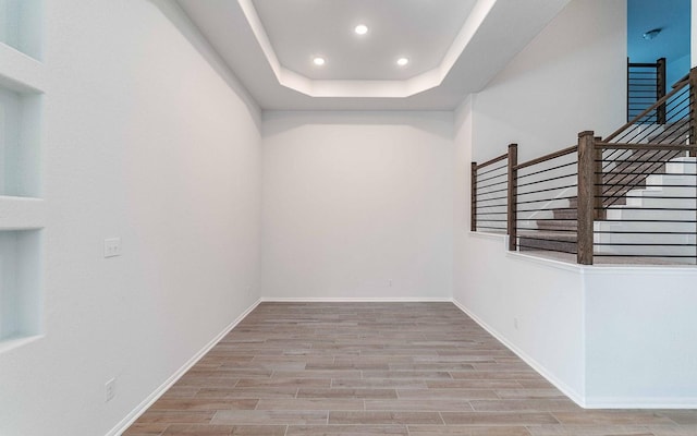 spare room featuring a raised ceiling and light hardwood / wood-style floors