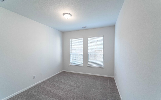 spare room with dark carpet and a textured ceiling