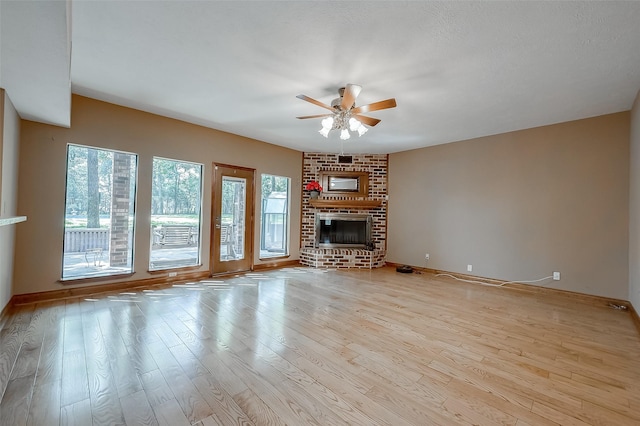 unfurnished living room with a textured ceiling, ceiling fan, light hardwood / wood-style floors, and a fireplace