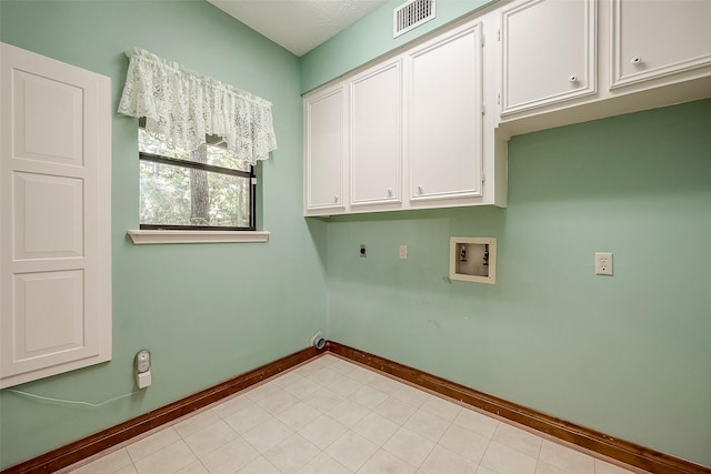 clothes washing area featuring electric dryer hookup, hookup for a washing machine, light tile patterned floors, and cabinets