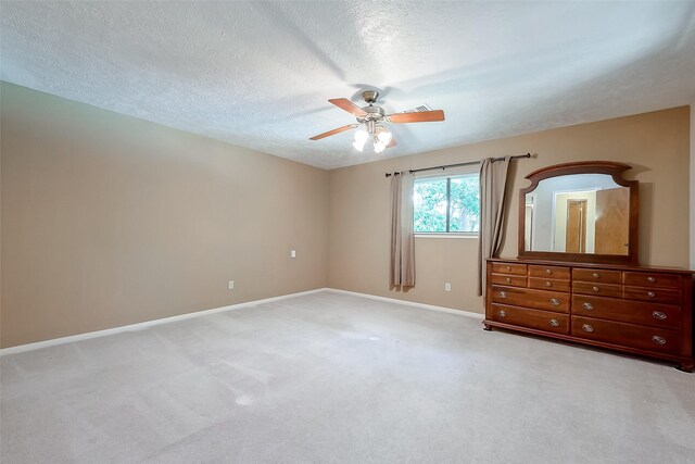 unfurnished bedroom with ceiling fan, light carpet, and a textured ceiling