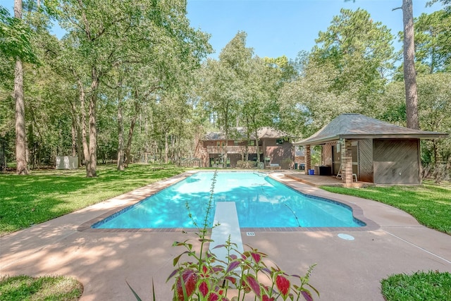 outdoor pool featuring a diving board, a patio area, a lawn, and an outdoor structure