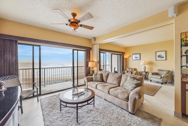 living room with a textured ceiling, ceiling fan, and light hardwood / wood-style floors