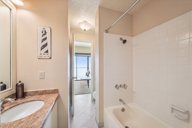 full bathroom with tiled shower / bath, tile patterned floors, toilet, vanity, and a textured ceiling